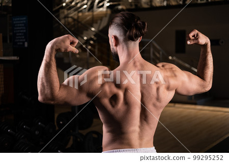 Athletic man shows muscular back and arms in gym Athletic man shows muscular back and arms in gym 99295252