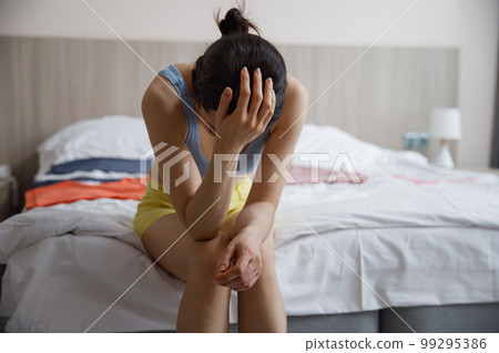 A frustrated woman covers her face with her hands while sitting alone in a room. The concept of separation. A frustrated woman covers her face with her hands while sitting alone in a room. The concept of separation. 99295386