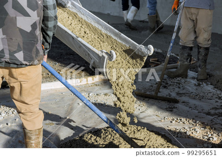 Concrete mixing truck pours out concrete for pavement surrounding new home Concrete mixing truck pours out concrete for pavement surrounding new home 99295651