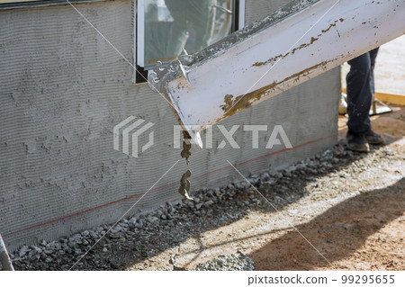 Mixing concrete truck pours concrete for pavement surrounding newly constructed house on building site Mixing concrete truck pours concrete for pavement surrounding newly constructed house on building site 99295655