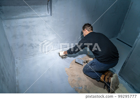 man applies insulation to a bathroom floor 99295777