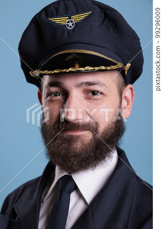 Aircraft captain wearing uniform and hat portrait, confident plane pilot standing with crossed arms, looking at camera. Smiling civil aviator with badge on professional suit Aircraft captain wearing uniform and hat portrait, confident plane pilot standing with crossed arms, looking at camera. Smiling civil aviator with badge on professional suit 99296009