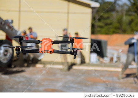 Construction site inspector is using drone to control pouring of concrete by employees near newly constructed house with help drone 99296162