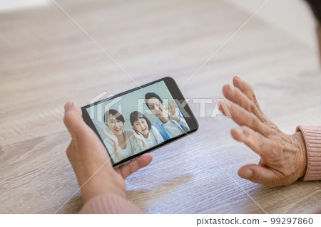 Hand of a senior woman making a video call with her family Hand of a senior woman making a video call with her family 99297860