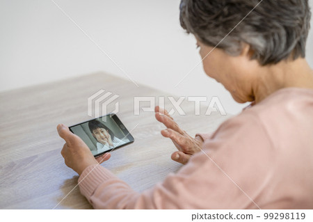 Hand of a senior woman making a video call with her grandson Hand of a senior woman making a video call with her grandson 99298119