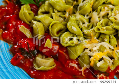 Closeup of green spinach tortellini with grated cheese and sauce Closeup of green spinach tortellini with grated cheese and sauce 99299114