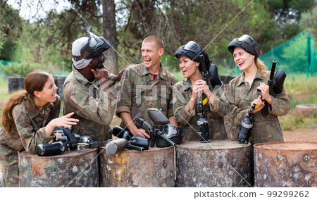 Smiling friends chatting after successful paintball match Smiling friends chatting after successful paintball match 99299262
