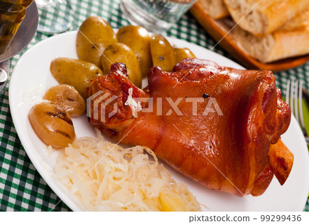 Appetizing pork knuckle and sauerkraut served with potatoes and onion Appetizing pork knuckle and sauerkraut served with potatoes and onion 99299436