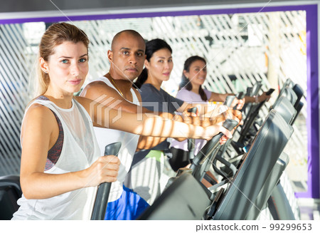 Woman training on elliptical trainer in gym 99299653