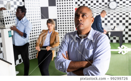 Group of people playing in quest room with focus to latino man Group of people playing in quest room with focus to latino man 99299726