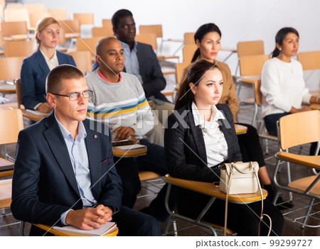 Business people listening to speaker at conference Business people listening to speaker at conference 99299727