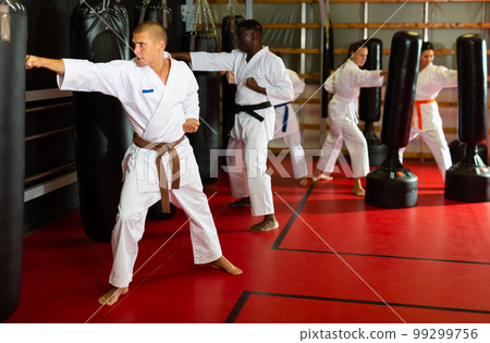 People exercising with punching bags during karate training 99299756