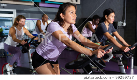 Group of adult people training on exercise bikes 99299757