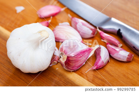 Garlic cloves on wooden table with kitchen knife Garlic cloves on wooden table with kitchen knife 99299785
