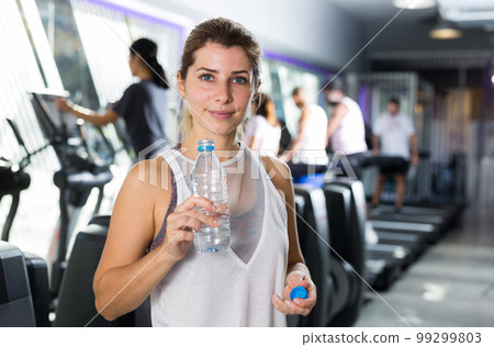 Woman standing with drinking water in gym 99299803