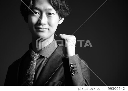 A young business person who turns his gaze while making a small fist pose Monochrome image 99300642