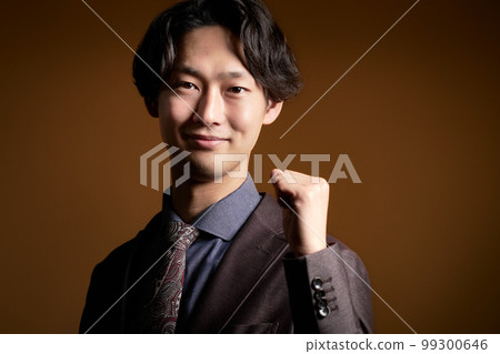 A young business person looking at you with a smile while holding a fist 99300646