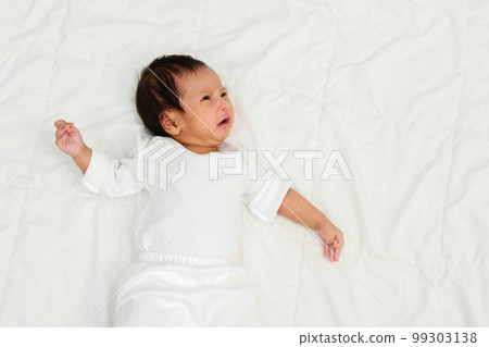 newborn baby lying and crying on bed 99303138