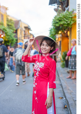 happy woman wearing Ao Dai Vietnamese dress, asian traveler sightseeing at Hoi An ancient town in central Vietnam. landmark and popular for tourist attractions. Vietnam and Southeast travel concept 99304388
