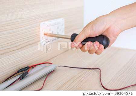 Man hand using screwdriver installing Wire cables for socket plug. Renovation, Repair, fixing and development of home and apartment concepts 99304571