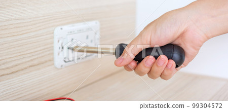 Man hand using screwdriver installing Wire cables for socket plug. Renovation, Repair, fixing and development of home and apartment concepts 99304572