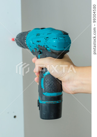 man using a cordless screwdriver assembling furniture at home, Carpenter working with electric screwdriver on the work 99304580