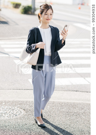 Working woman walking while holding a smartphone Working woman walking while holding a smartphone 99304938