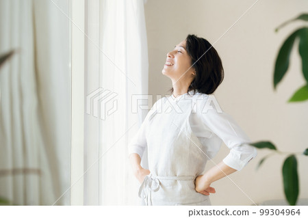 A middle-aged woman bathing in the sunlight by the window A middle-aged woman bathing in the sunlight by the window 99304964