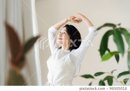 A middle-aged woman bathing in the sunlight by the window 99305018