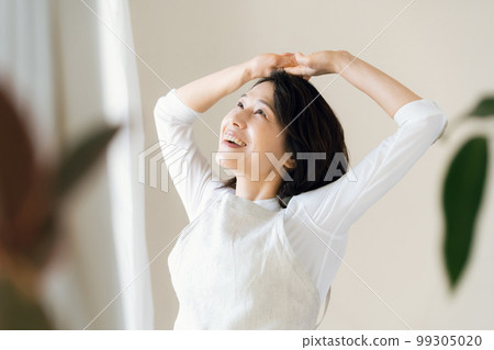 A middle-aged woman bathing in the sunlight by the window A middle-aged woman bathing in the sunlight by the window 99305020