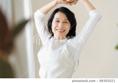 A middle-aged woman bathing in the sunlight by the window A middle-aged woman bathing in the sunlight by the window 99305021