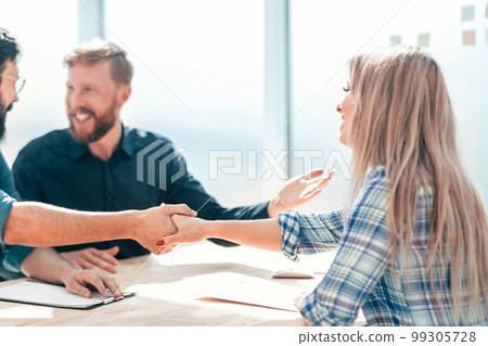 employer shaking hands with a young woman during the interview. 99305728