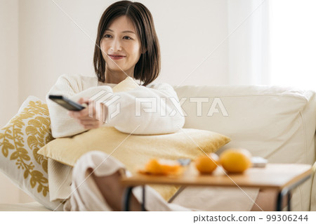 A housewife relaxing in the room, a woman watching TV 99306244