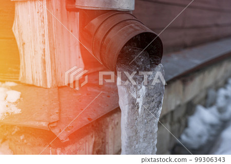 frozen water in downspout gutter of the roof drainage system with ice 99306343