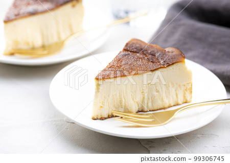 亮桌上的巴斯克芝士蛋糕和金叉 亮桌上的巴斯克芝士蛋糕和金叉 99306745