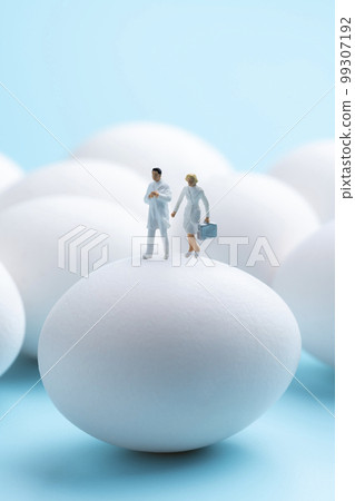 Raw egg and miniature doctor on light blue background Raw egg and miniature doctor on light blue background 99307192