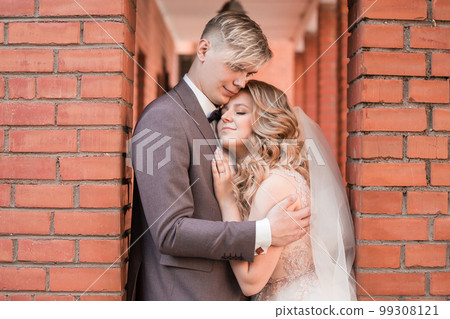 happy newlywed couple hugging each other while walking 99308121