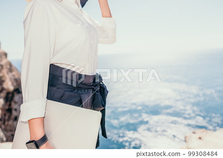 Woman sea laptop. Business woman in yellow hat freelancer with laptop working over blue sea beach. Girl relieves stress from work. Freelance, digital nomad, travel and holidays concept 99308484