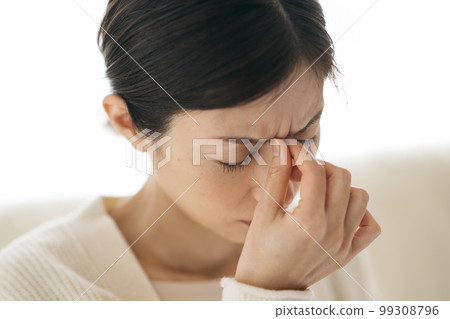 A woman suffering from itchy eyes due to headache and hay fever A woman suffering from itchy eyes due to headache and hay fever 99308796