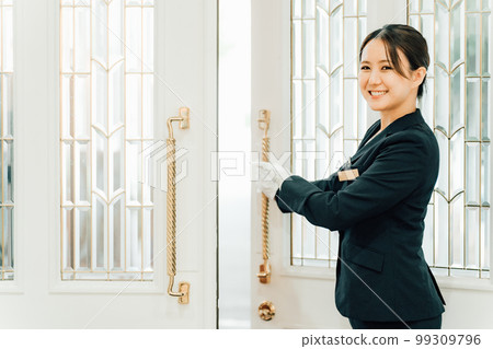 Wedding planner, door staff, hotelier woman who opens the door of the wedding hall (wedding staff) Wedding planner, door staff, hotelier woman who opens the door of the wedding hall (wedding staff) 99309796