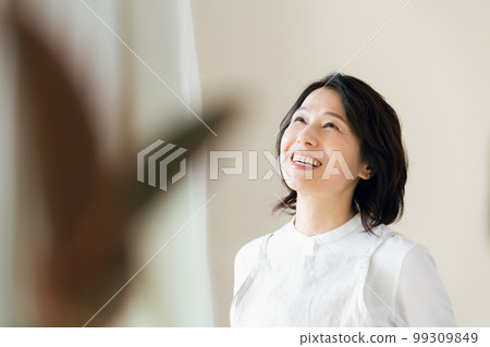 A middle-aged woman bathing in the sunlight by the window A middle-aged woman bathing in the sunlight by the window 99309849