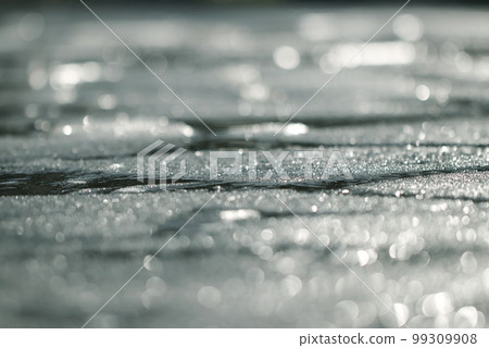 A low angle image of a frozen lake surface that reflects glitter and light. 99309908