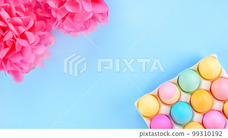 Colorful Easter eggs pack and pink paper decor on blue background with space for text. Spring flat lay. Pastel painted eggs in box. Colorful Easter eggs pack and pink paper decor on blue background with space for text. Spring flat lay. Pastel painted eggs in box. 99310192