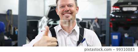 Happy smiling auto mechanic showing thumbs up gesture in workshop Happy smiling auto mechanic showing thumbs up gesture in workshop 99310883