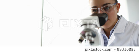 Young woman scientist looks into microscope in laboratory Young woman scientist looks into microscope in laboratory 99310885