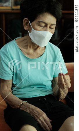 Elderly woman looking at thermometer After taking the fever 99311875