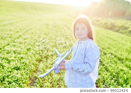 Sincere emotions. Happy little girl running on the field with blue toy plane in their hands. 99312424