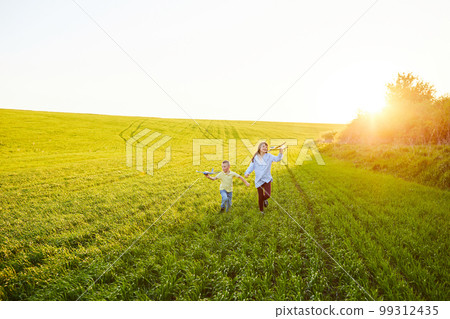 Cheerful and happy children play in the field and imagine themselves to be pilots on a sunny summer day. Kids dreams of flying and aviation. 99312435