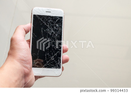 Hand holding mobile phone with broken glass screen Hand holding mobile phone with broken glass screen 99314433