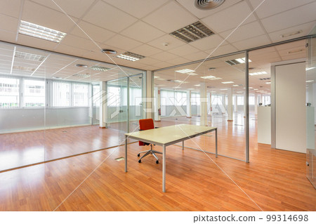 In a bankrupt office building, one of the many empty rooms with transparent, solid glass wall panels and an outdated ceiling covering is in need of repair and refurbishment. In a bankrupt office building, one of the many empty rooms with transparent, solid glass wall panels and an outdated ceiling covering is in need of repair and refurbishment. 99314698